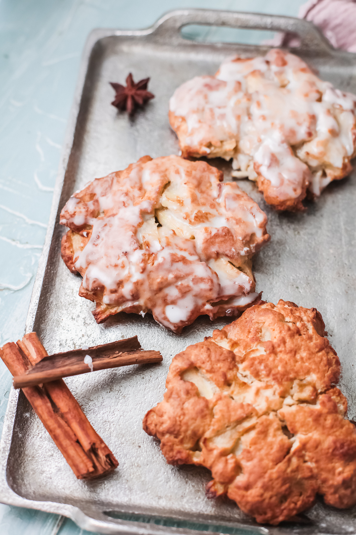 three completed apple fritters on a baking tray