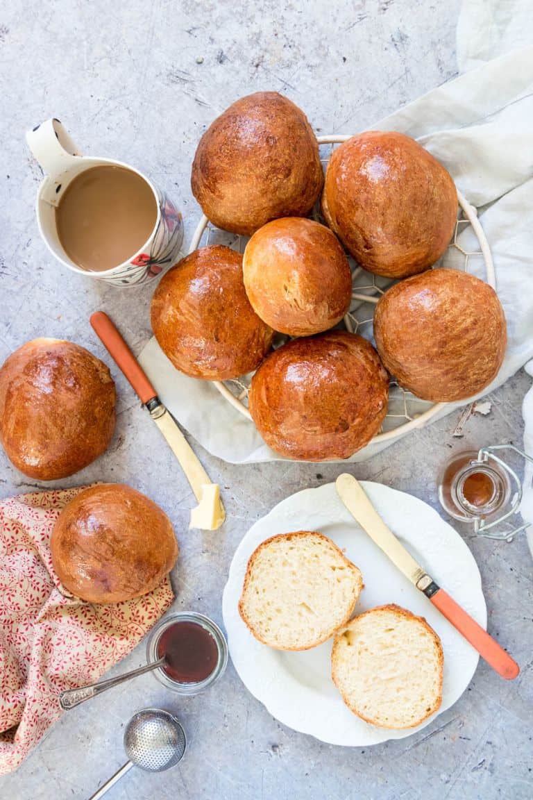 overhead view of orange cardamom buns on a rack, on a white plate, and on a towel