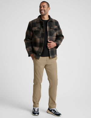 model wearing a men's plaid button-up jacket over a black shirt on a light gray background. 