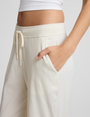 Woman wearing a white corduroy pants outfit on a grey background. 