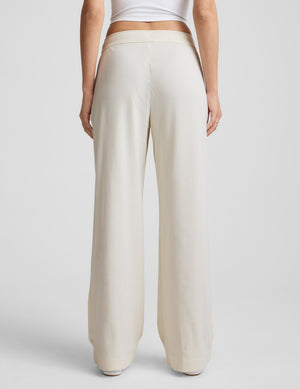 Woman wearing a white corduroy pants outfit on a grey background. 