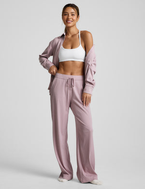 Pink corduroy lounge pants worn by a person on a light gray background. 