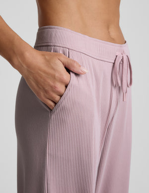 Pink corduroy lounge pants worn by a person on a light gray background. 