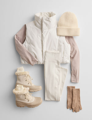 winter clothing set including a puffer jacket, leggings, boots, and beanie on a light gray background. 