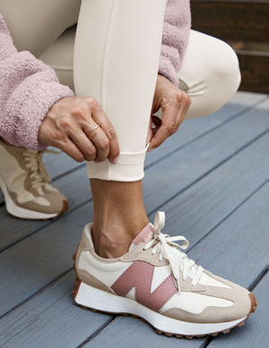 close-up of a person wearing a pink fleece jacket and white leggings with a blurred background.