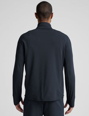 man wearing a dark blue quarter zip pullover against a plain background. 