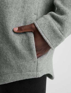 woman wearing a gray shirt jacket against a plain background. 