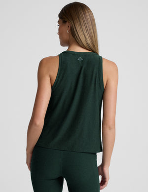 model wearing a green relaxed fit tank top and leggings against a plain background. 