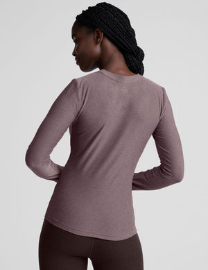model wearing a mauve long-sleeve fitted crew neck top against a plain background.