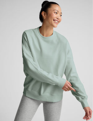 model wearing a light blue oversized crew neck fleece sweatshirt against a plain background. 