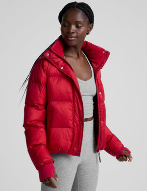 woman wearing a red puffer jacket on a plain background. 