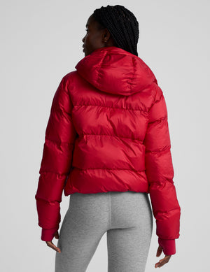 woman wearing a red puffer jacket on a plain background. 