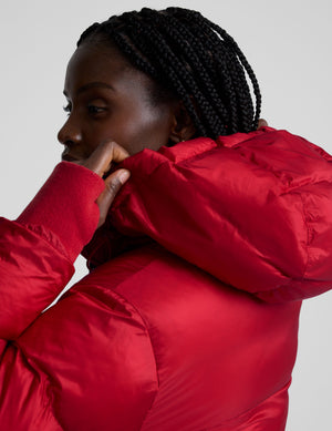 woman wearing a red puffer jacket on a plain background. 