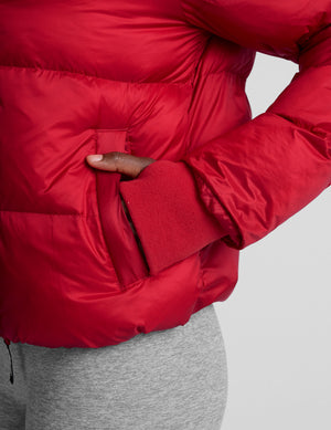woman wearing a red puffer jacket on a plain background. 