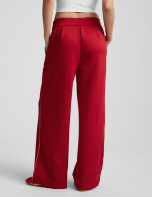Red wide-leg pants with white piping on a light gray background. 