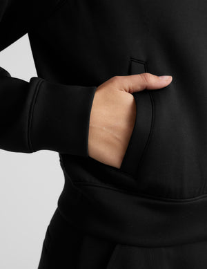 Woman wearing a black tracksuit on a light gray background. 