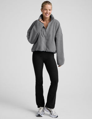 model wearing a gray fleece zip-up jacket against a plain background. 