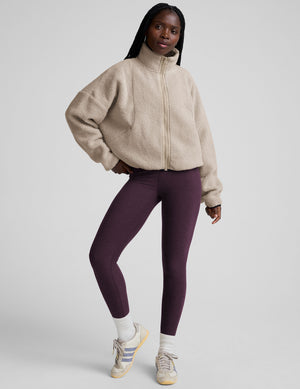 model wearing a beige zip-up fleece jacket against a plain background. 