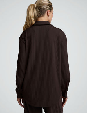 model wearing a brown ribbed button down top and brown ribbed pants against a plain background. 