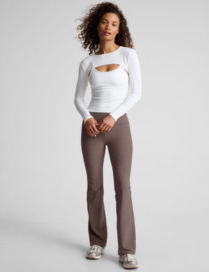woman wearing brown high-waisted bootcut pants against a plain background. 