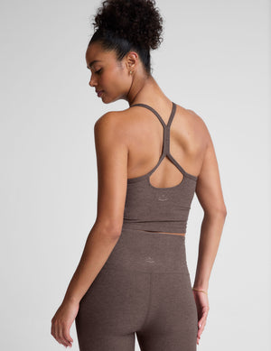 Woman wearing a brown racerback cropped tank and leggings on a light gray background. 