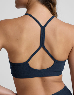 person wearing a blue slim racerback bra with leggings against a plain background. 