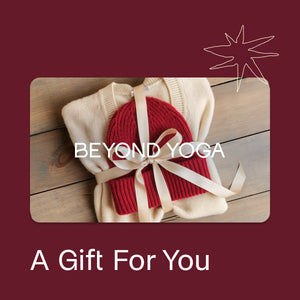 Red knitted hat with beige scarf on a wooden surface, branded 'Beyond Yoga'.
