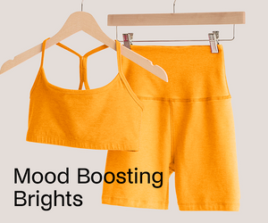 Orange sports bra and shorts set on hangers with 'Mood Boosting Brights' text.